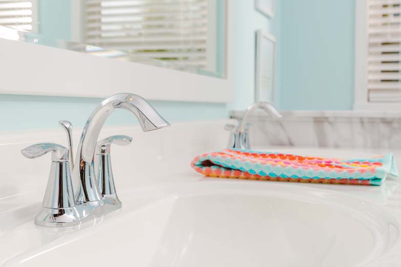two sink faucets with mirror in light blue bathroom