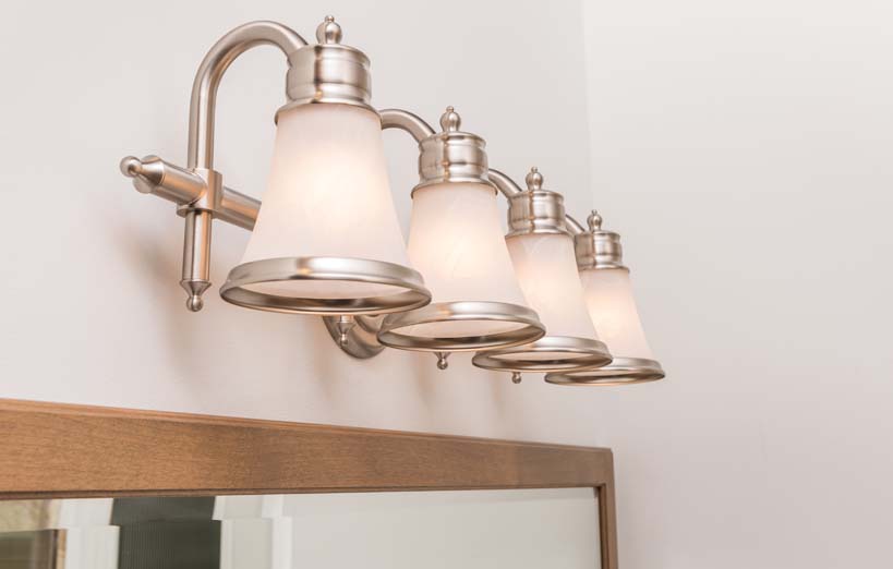 close up of four wall lights above brown mirror
